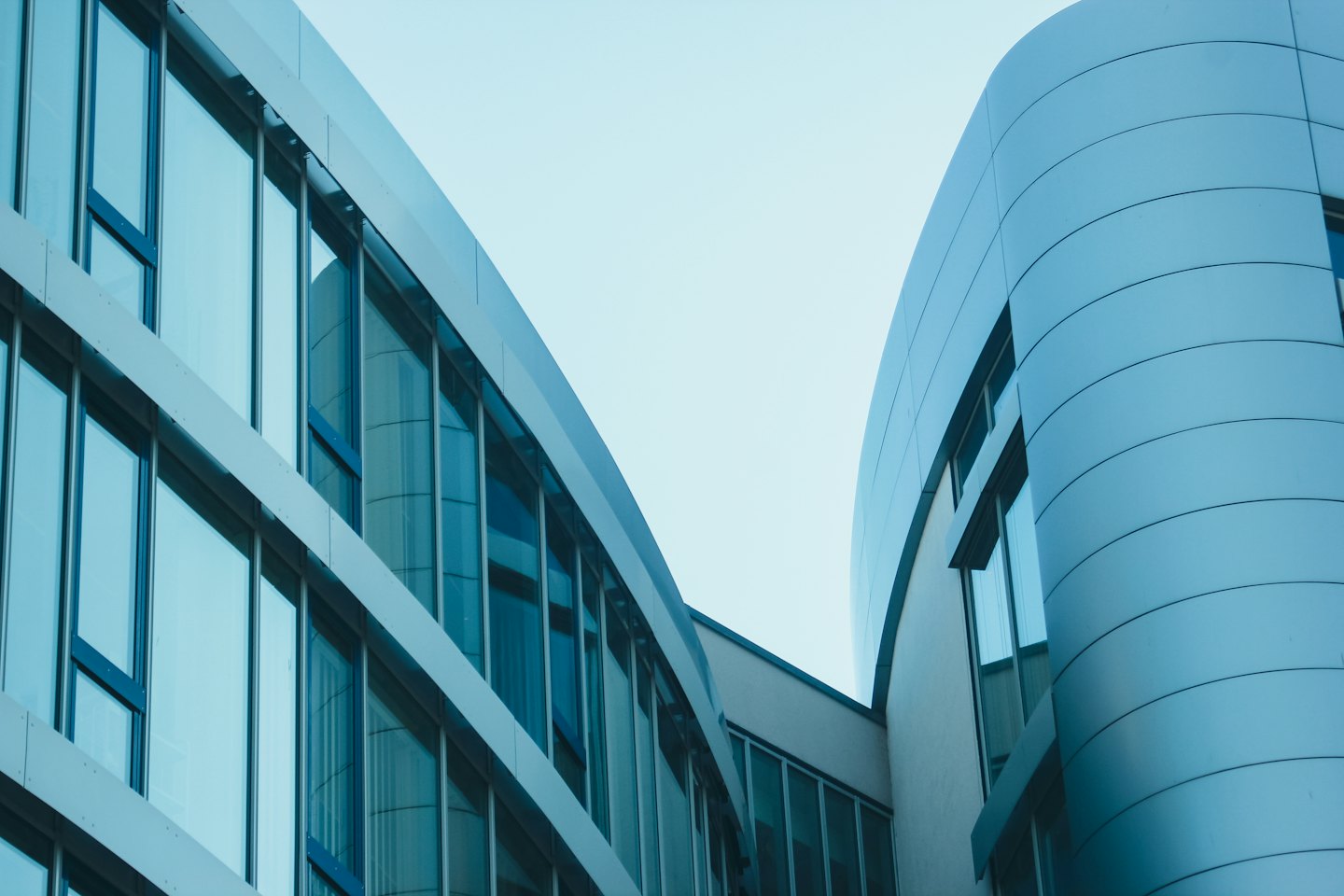 Modern office building with curved silver paneling and blue glass.