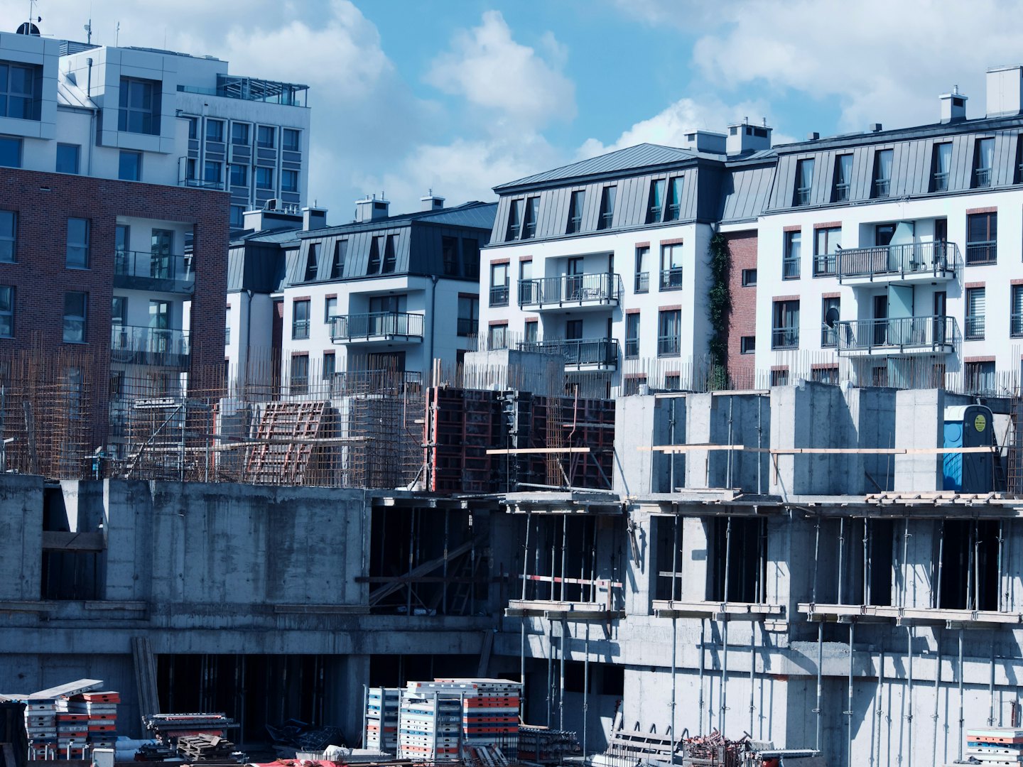 Modern apartment buildings under construction beside finished residential housing.