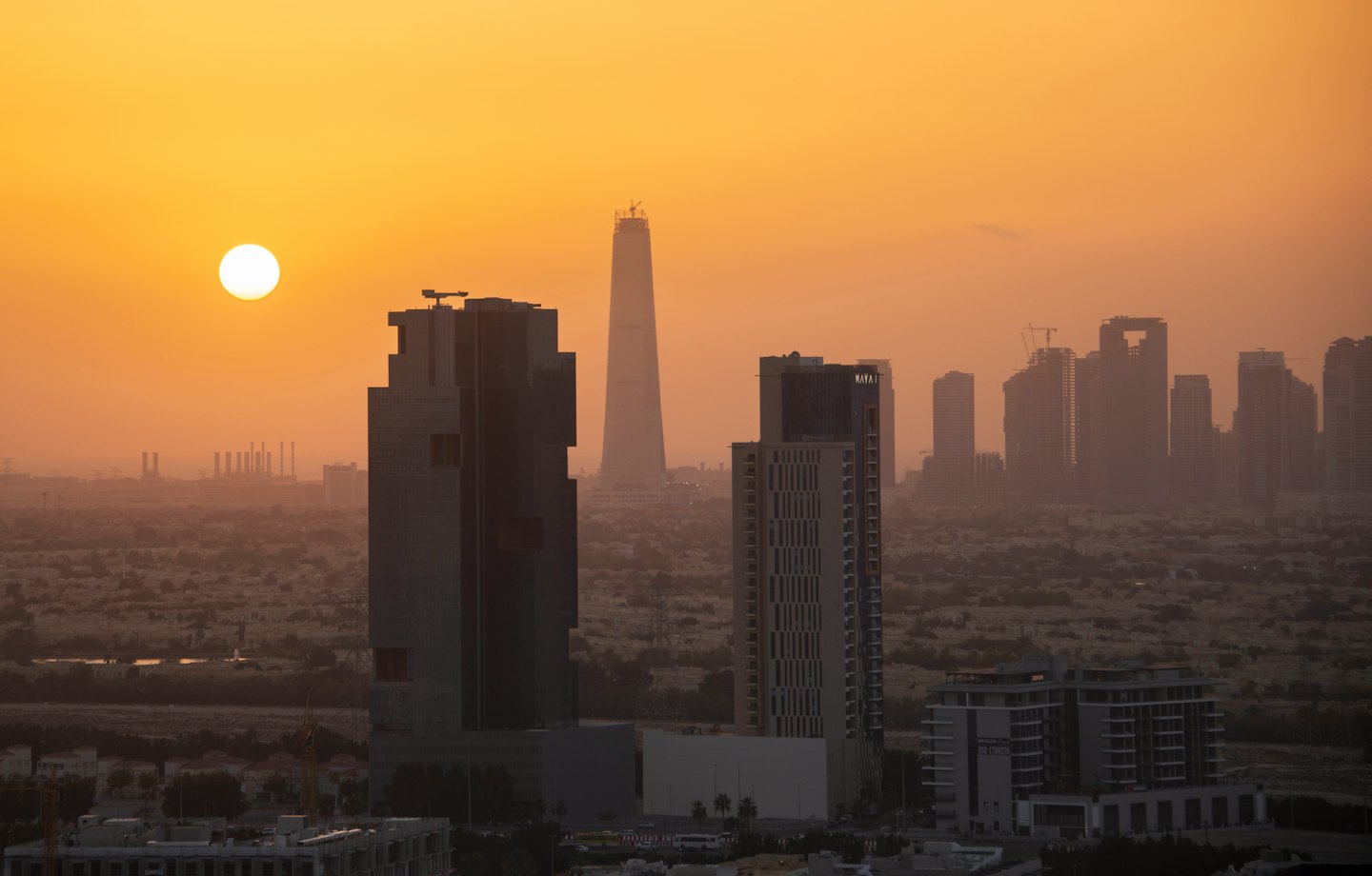 Aerial view of city skyline at sunset with buildings under construction.